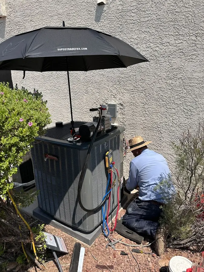 HVAC technician performing outdoor AC maintenance in Kelso