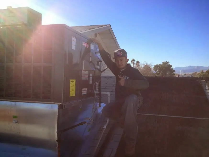 HVAC technician performing Air Duct Cleaning on a rooftop unit in Kelso